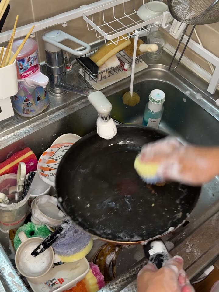 洗い物でいっぱいのシンクでスクラブダディを使ってフライパンを洗っている21回戦の映像